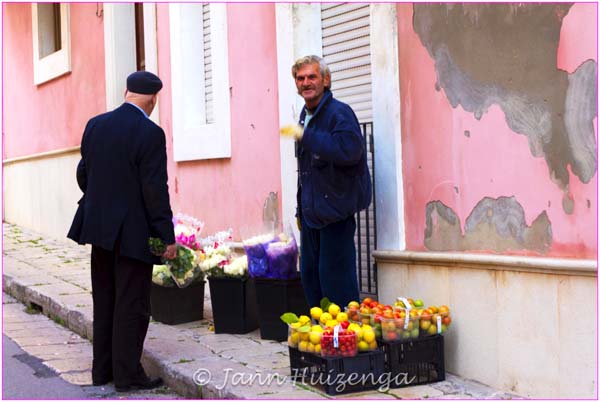Vendor on Pink Wall in Ragusa, SIcily, copyright Jann Huizenga